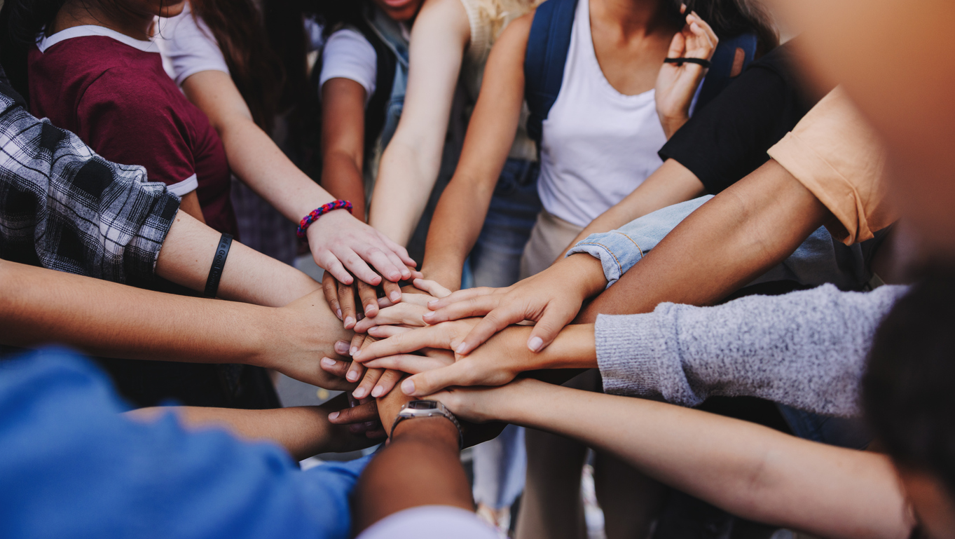 Multicultural teenagers putting their hands together in a huddle. Group of unrecognizable young people expressing their unity and teamwork