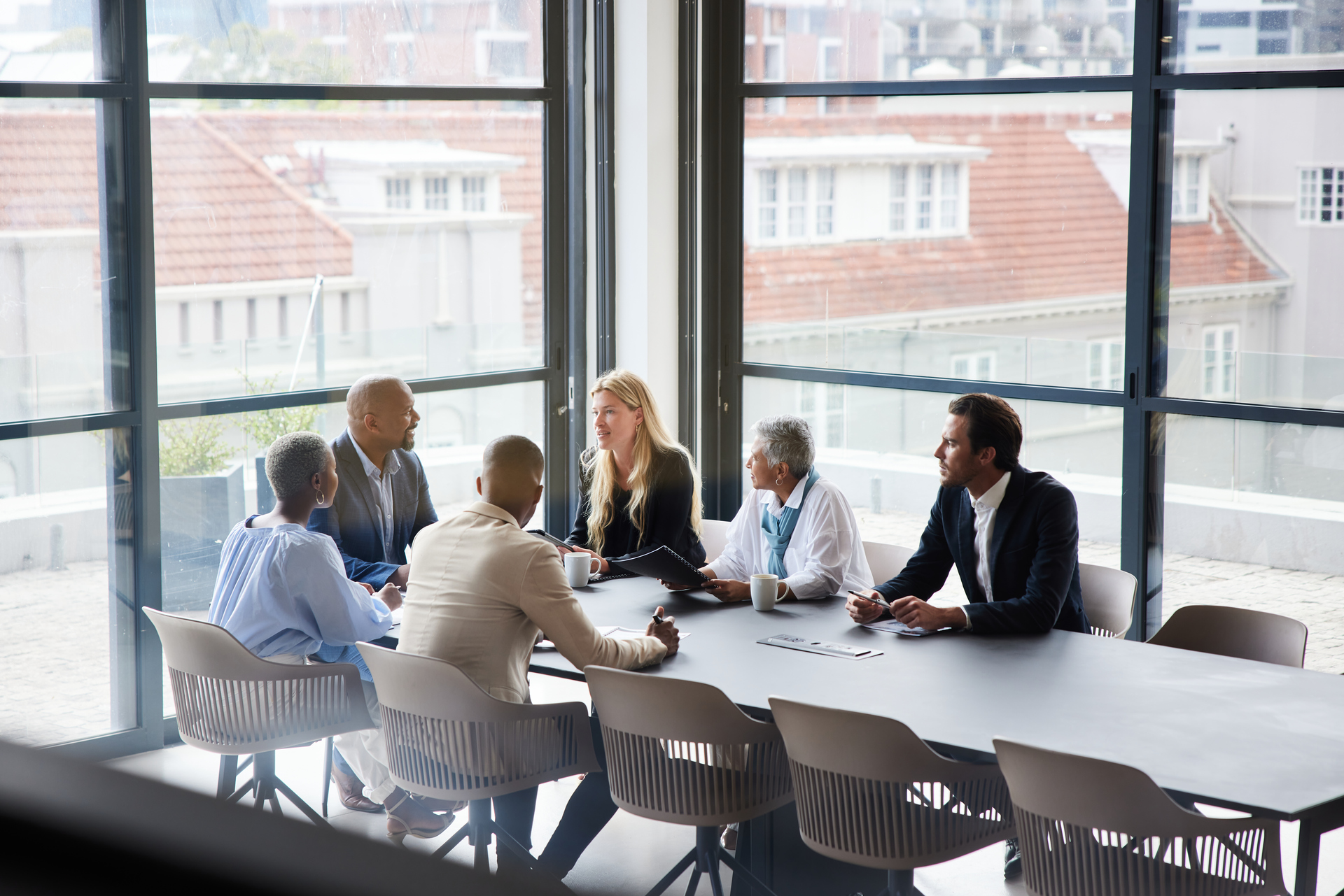 Diverse group of businesspeople talking together around a conference table during a boardroom meeting in a modern office
